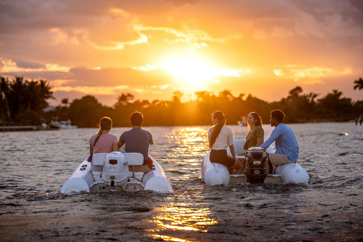 Two inflatable boats powered by Suzuki 25 HP outboard motors cruising at sunset on calm water.