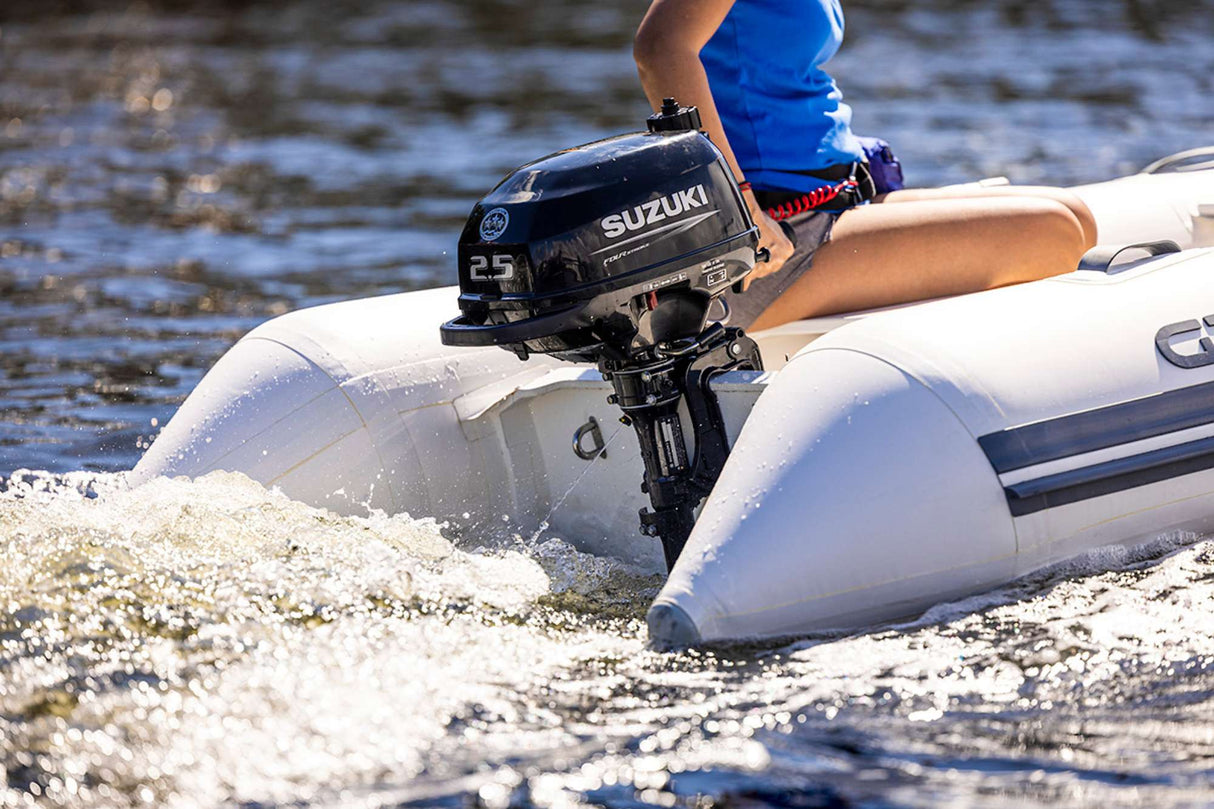 Suzuki 2.5 HP outboard motor mounted on an inflatable boat in motion on the water.