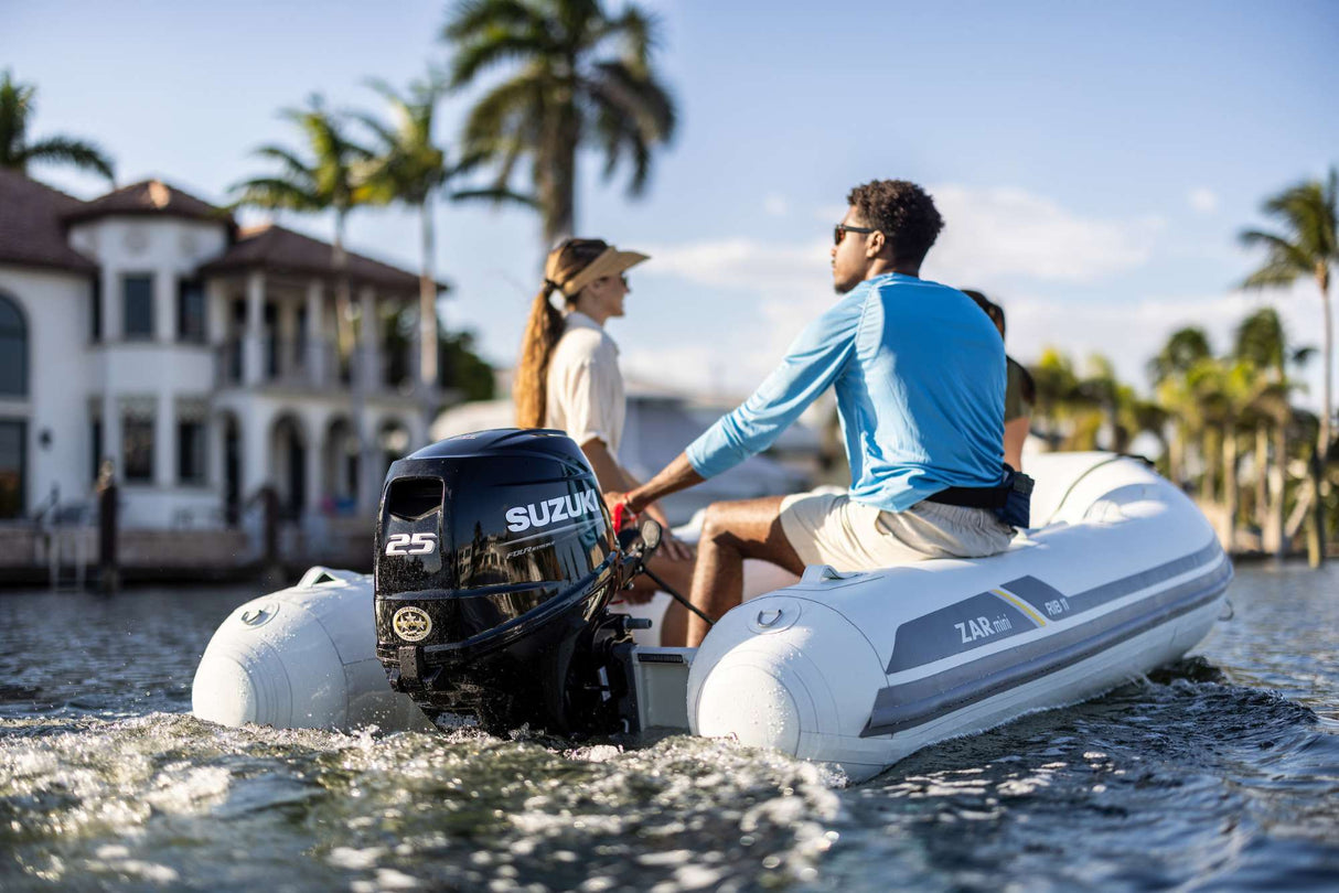 Suzuki 25 HP outboard motor mounted on a mini inflatable boat cruising near waterfront homes.