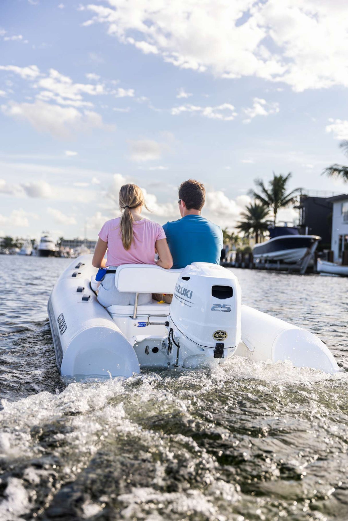 Couple cruising a canal in a inflatable boat powered by a white Suzuki 25 HP outboard motor.