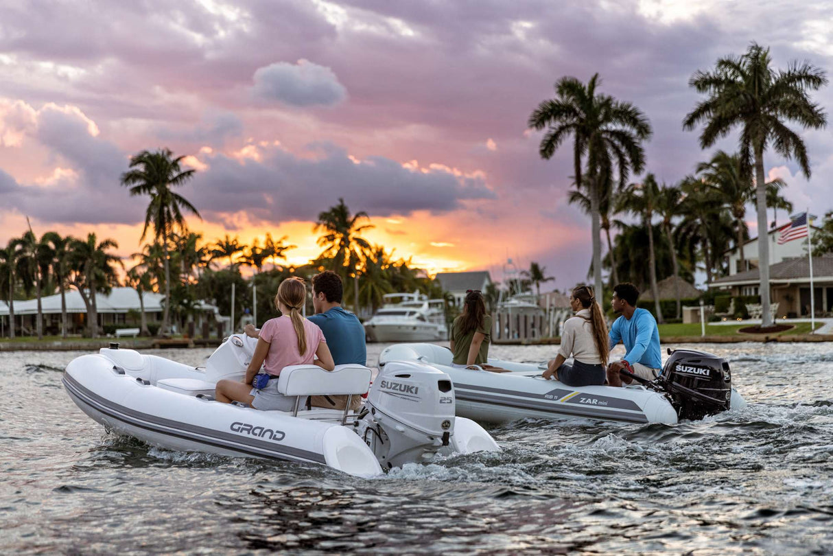 Suzuki 25 HP outboard motors powering two inflatable boats cruising at sunset near waterfront homes.