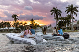 Suzuki 25 HP outboard motors powering two inflatable boats cruising at sunset near waterfront homes.