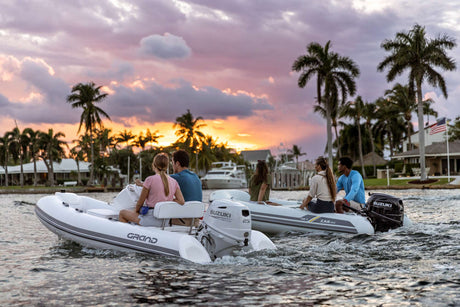 Suzuki 25 HP outboard motors powering two inflatable boats cruising at sunset near waterfront homes.