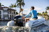 Suzuki 25 HP outboard motor mounted on a mini inflatable boat cruising near waterfront homes.
