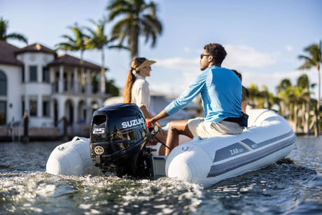 Suzuki 25 HP outboard motor mounted on a mini inflatable boat cruising near waterfront homes.